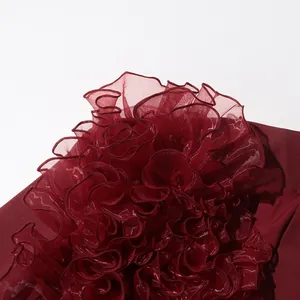Close-up of elegant burgundy jacket showing exquisite ruffled organza stitching texture.