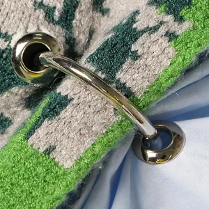 Macro-opname van gepolijste zilveren ringhardware op groen gebreide stof van een patchwork shirt
