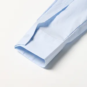 Detailopname van de knoop en de manchet van de mouw op een lichtblauw katoenen shirt