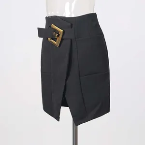 Detail of black high-waisted slit skirt with large elegant gold metal buckle.