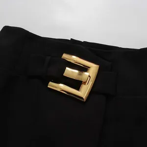 Close-up of black elegant skirt featuring a decorative gold E-shaped metal buckle.