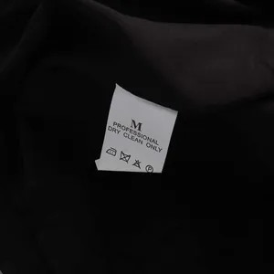 Close-up detail of clothing care label with washing symbols and size M on black fabric