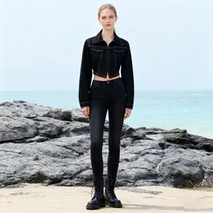 Stilvolle, eng geschnittene schwarze Denim-Kurzjacke mit passender Jeans am felsigen Strand.