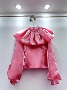 Detailed view of an elegant pink satiny blouse featuring a dramatic ruffled puff collar design