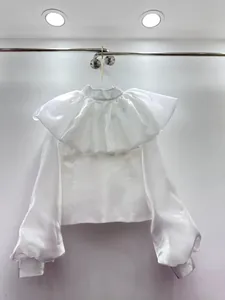 Detailed view of elegant white long-sleeve blouse with large ruffle collar detail