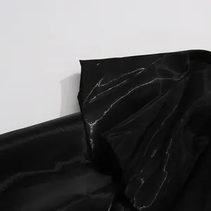 Close-up of glossy black fabric texture showing the high-end material of the shirt