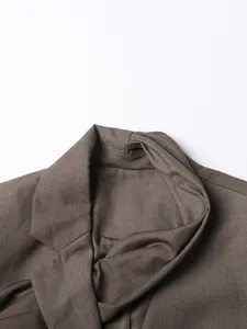 Primer plano de una chaqueta blazer marrón con cuello chal y detalle de la tela tejida