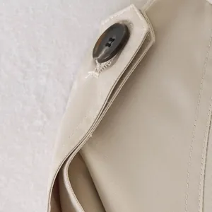 Close-up of buttons and precision stitching on a beige British style trench coat.