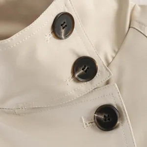 Close-up of brown tortoiseshell buttons and beige fabric on a classic trench coat