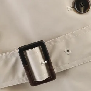 Close-up detail of khaki British style trench coat belt buckle and premium fabric texture