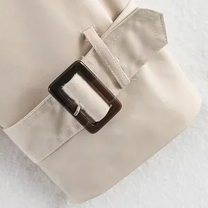 Detail of British style trench coat cuff with dark tortoiseshell buckle and beige fabric.