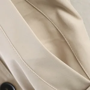 Close-up detail of high-quality stitching and pocket on a beige British style trench coat.