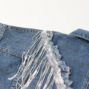 Detailansicht der silbernen Paillettenfransen und ausgefransten Kanten an einer Jeansjacke