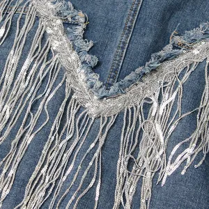 Nahaufnahme der glitzernden silbernen Paillettenfransen an einer blauen Jeansjacke Damen
