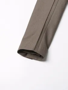 Detalle del puño de la manga de un blazer marrón con textura de tela fina y costura limpia.