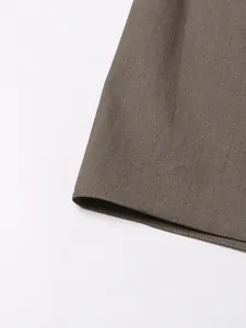 Vista detallada del tejido texturizado marrón y el dobladillo de un blazer para mujer
