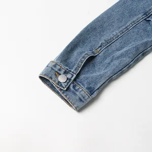 Nahaufnahme von Jeansjacken-Manschette mit Metallknopf und blauer Textur