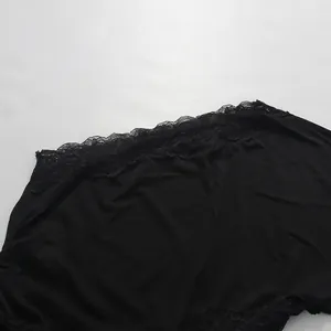 Close-up of delicate black lace stitching on the hem of a stylish asymmetric dress.