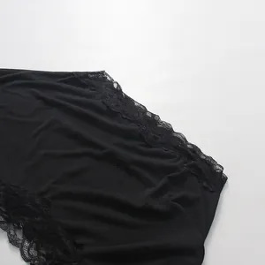 Close-up of black lace patchwork detail on irregular shoulder dress design.