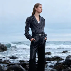 Elegant vintage V-neck blouse with lantern sleeves and bead details on rocky beach