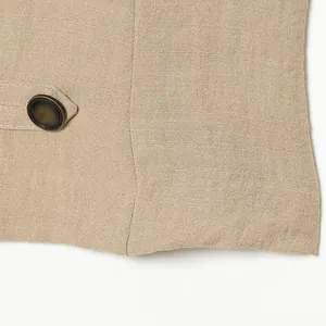 Vue détaillée d'un bouton vintage et d'un tissu en lin sur un gilet beige chic