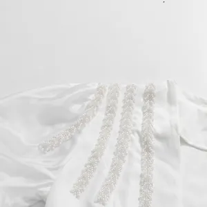 Intricate detail of elegant pearl and bead embroidery on white lantern sleeve shirt