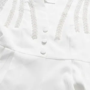 Close-up of elegant V-neck blouse featuring intricate white beadwork and buttons