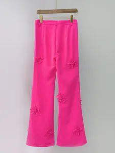 Eleganti pantaloni a gamba larga rosa acceso con applicazioni floreali 3D su sfondo bianco
