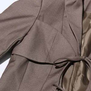 Dettaglio ravvicinato di un blazer marrone da donna con design traforato e laccio