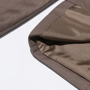 Macro dettaglio della fodera marrone liscia e del tessuto strutturato di un blazer da donna.