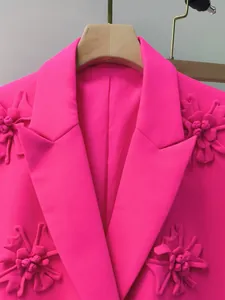 Dettaglio di blazer rosa acceso con applicazioni floreali 3D e rever a lancia