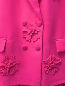 Dettaglio ravvicinato di un blazer rosa con applicazioni floreali 3D artigianali