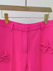 Dettaglio ravvicinato di eleganti pantaloni fucsia con applicazioni floreali in 3D