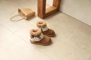 Detailed close-up of brown toddler girls' winter boots featuring lace trim and bow accents.