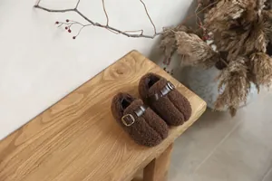 Detailed macro view of brown fuzzy pig trotter slippers for kids on a wooden bench