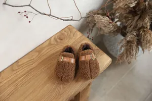 Detailed macro view of brown fuzzy plush children's shoes with buckle strap details