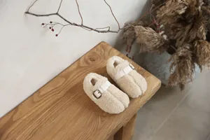 Cozy fleece-lined kids Tabi shoes with leather buckle detail shown on a wooden bench
