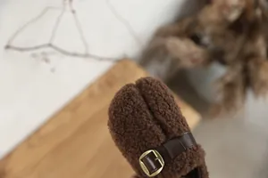 Close-up of children's brown sherpa fleece split-toe shoes with buckle detail.