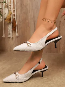 Detailed view of white tweed pointed-toe slingback heels with elegant metal buckle.