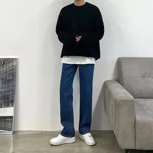 Detail of men's loose blue straight leg jeans styled with a black cable knit sweater
