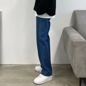 Side view of men's loose fit blue denim jeans paired with white sneakers