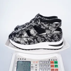 Macro detail view of women's floral platform sandals showing product weight on digital scale.