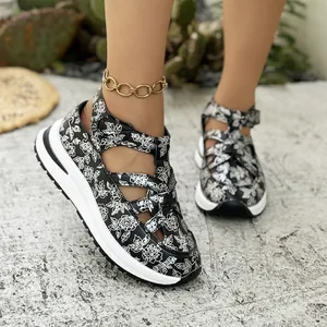 Close-up of floral print platform Roman sandals with Velcro straps on outdoor ground.