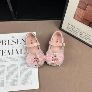 Close-up of pink sequined girls princess shoes with large organza bow and cherry charm
