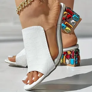 Detail van witte slippers met krokodillenprint en kleurrijke blokhakken met strass