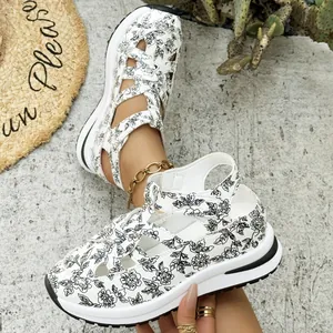 Close-up detail of white and black floral print platform wedge sandals with Velcro straps