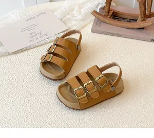 Detailed macro view of children's tan sandals featuring three buckles and a cork sole