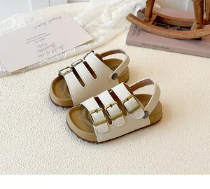 Close-up of children's beige sandals featuring three metal buckles and a comfortable cork sole.