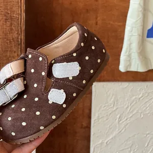 Close-up detail of brown suede-like girls' polka dot shoe featuring velcro straps