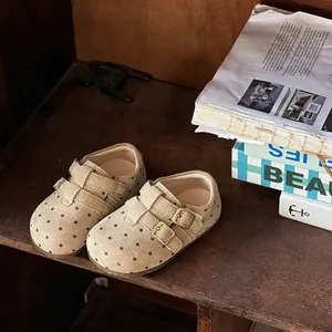 Close-up of girls' polka dot suede loafers with double buckle straps